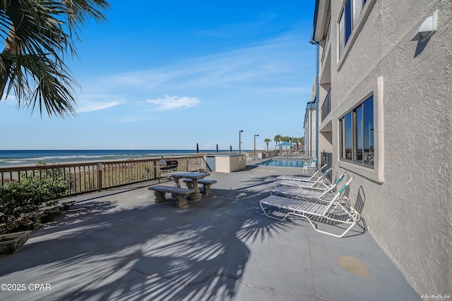 view of patio featuring a water view and a beach view