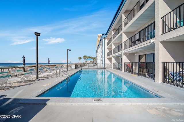 community pool featuring a water view, a patio, and fence