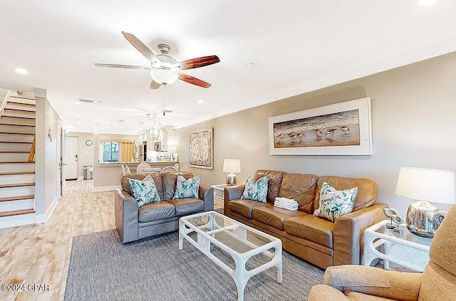 living area featuring baseboards, light wood-style flooring, ceiling fan, stairway, and recessed lighting