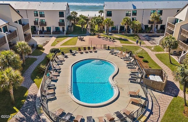 community pool featuring a patio area, a water view, and fence