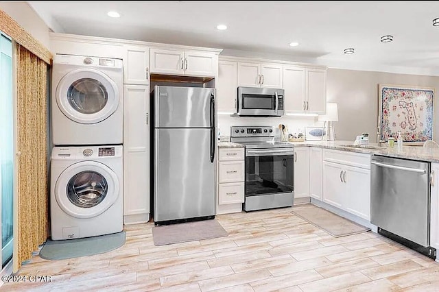 kitchen with white cabinets, light stone countertops, stainless steel appliances, light wood-type flooring, and stacked washing maching and dryer