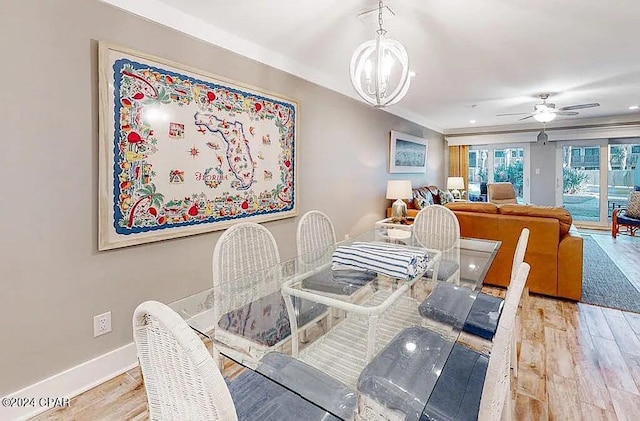 dining room with baseboards, wood finished floors, and ceiling fan with notable chandelier