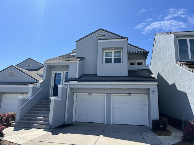 view of front of property with driveway, a tile roof, a garage, and stucco siding