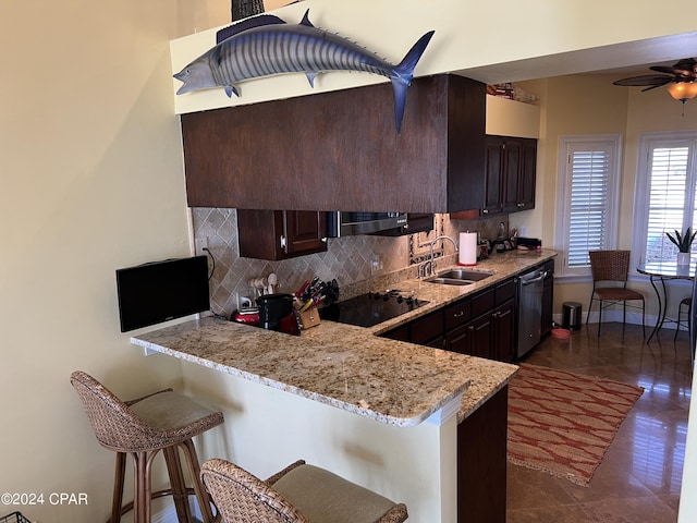 kitchen featuring dishwashing machine, a breakfast bar area, black electric cooktop, a sink, and tasteful backsplash