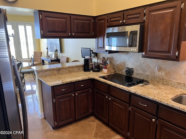 kitchen featuring light stone counters, a peninsula, dark brown cabinets, appliances with stainless steel finishes, and tasteful backsplash