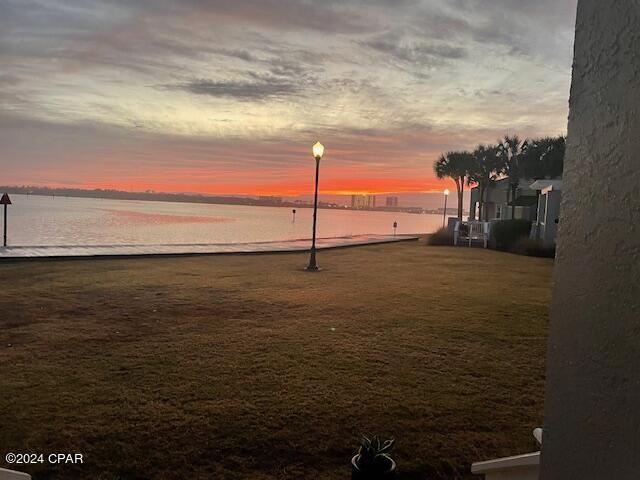 yard at dusk featuring a water view