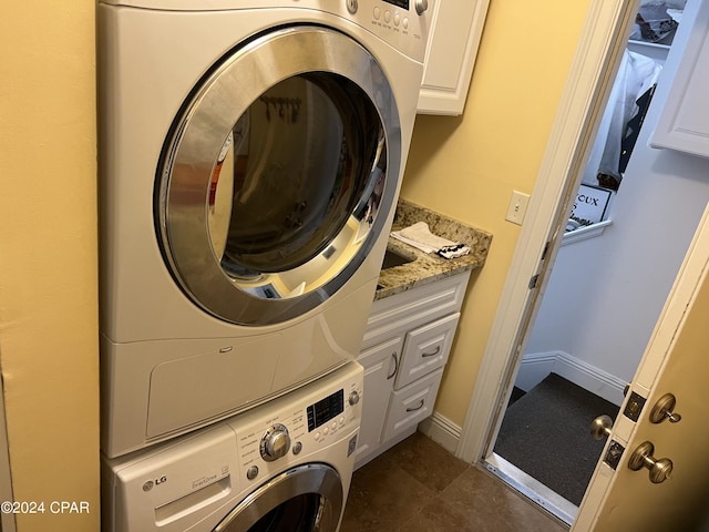 washroom with stacked washing maching and dryer, cabinet space, and baseboards