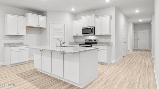 kitchen with appliances with stainless steel finishes, white cabinets, a sink, and light wood-style flooring