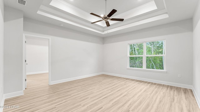 unfurnished room with light wood-style floors, a tray ceiling, and ornamental molding