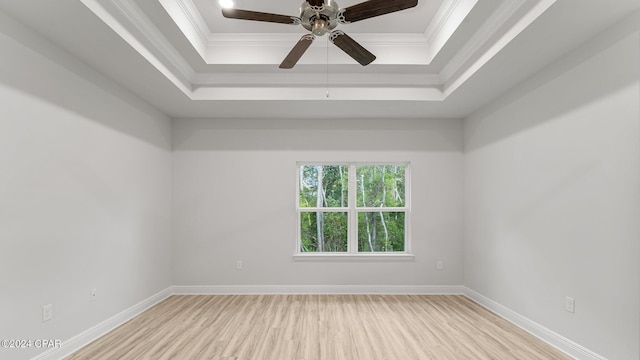 spare room with baseboards, a tray ceiling, wood finished floors, and ornamental molding