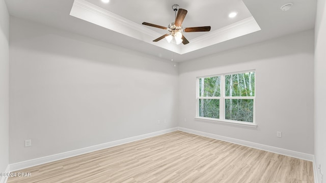 spare room featuring ceiling fan, wood finished floors, baseboards, ornamental molding, and a tray ceiling