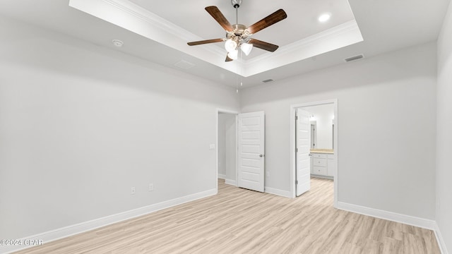 unfurnished bedroom featuring a tray ceiling, crown molding, light wood finished floors, visible vents, and baseboards