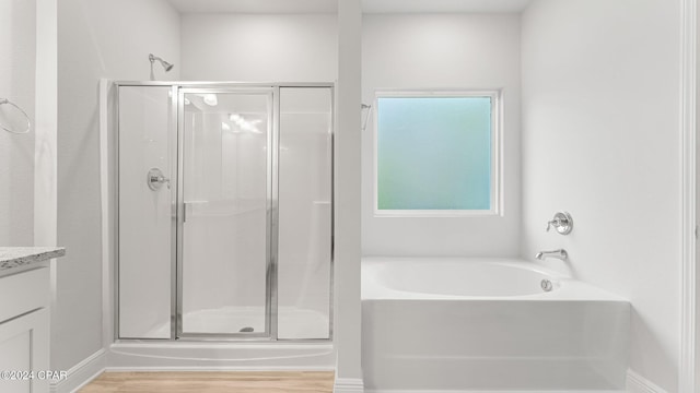 bathroom featuring a garden tub, wood finished floors, vanity, baseboards, and a shower stall