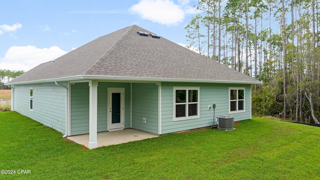 rear view of property featuring a shingled roof, a patio area, a lawn, and central air condition unit