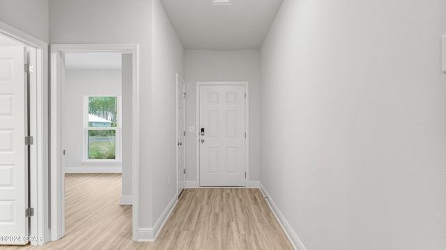 hall with baseboards and light wood-style floors