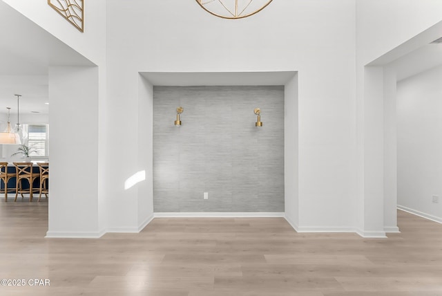 interior space with an accent wall, baseboards, and wood finished floors