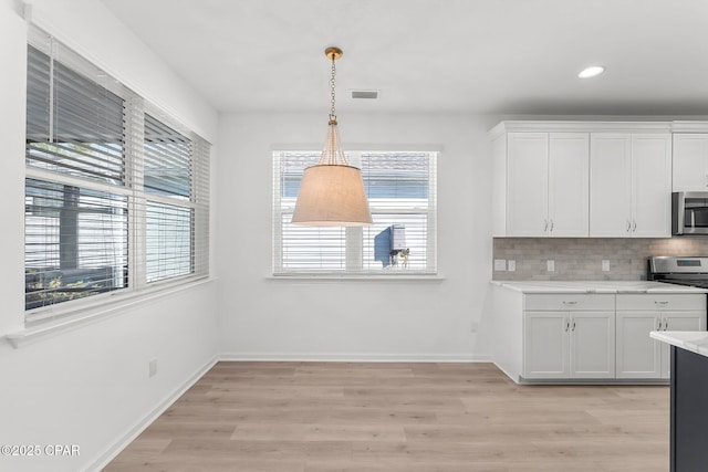 kitchen with tasteful backsplash, visible vents, light wood-style floors, white cabinets, and stainless steel appliances