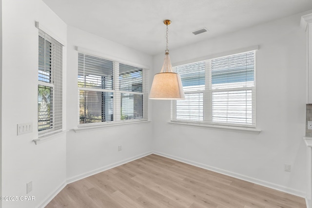 unfurnished dining area with light wood-style flooring, baseboards, and visible vents