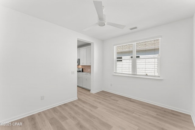 unfurnished room featuring visible vents, baseboards, light wood-type flooring, and a ceiling fan