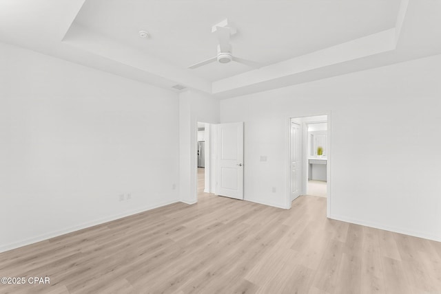 unfurnished bedroom featuring baseboards, a raised ceiling, ceiling fan, and light wood finished floors