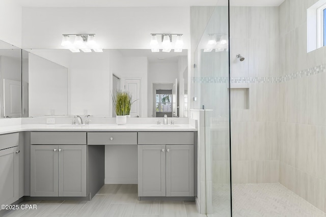 full bathroom with double vanity, a walk in shower, and a sink