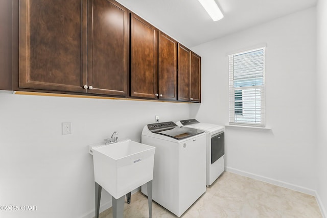 laundry area featuring washer and dryer, cabinet space, baseboards, and a sink