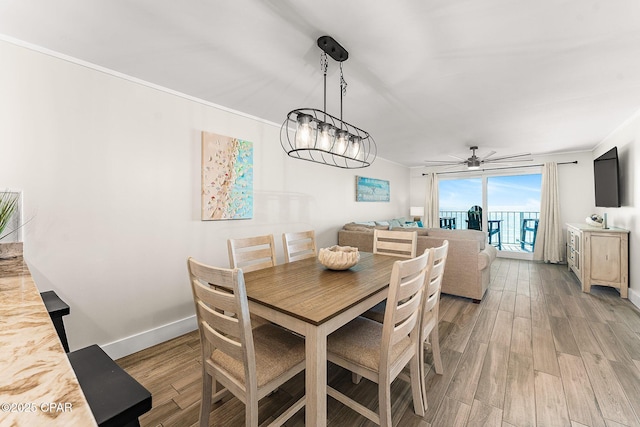 dining space with baseboards, light wood-type flooring, a ceiling fan, and crown molding