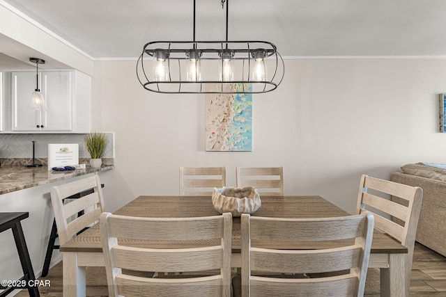 dining space with ornamental molding, an inviting chandelier, and wood finished floors