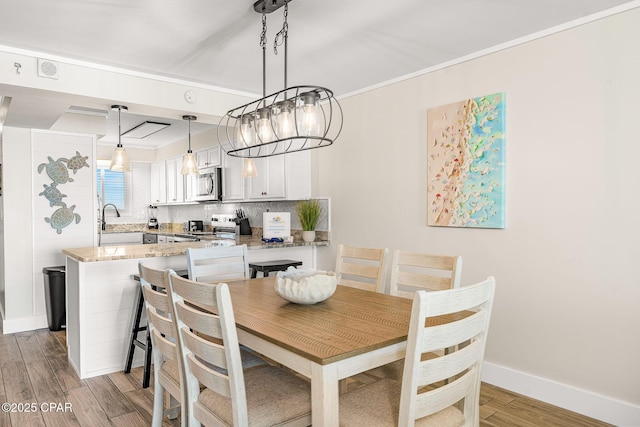 dining room with baseboards, wood finished floors, and ornamental molding