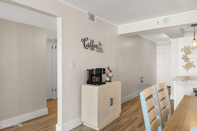 dining area featuring light wood-style flooring, visible vents, ornamental molding, and baseboards