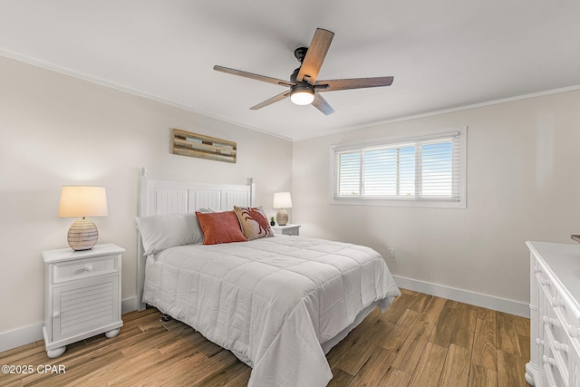 bedroom with crown molding, light wood finished floors, a ceiling fan, and baseboards