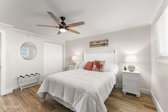 bedroom featuring ornamental molding, a closet, baseboards, and wood finished floors