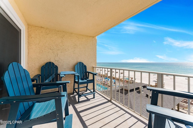 balcony featuring a water view and a beach view