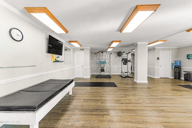 exercise area with crown molding, visible vents, a textured ceiling, wood finished floors, and baseboards