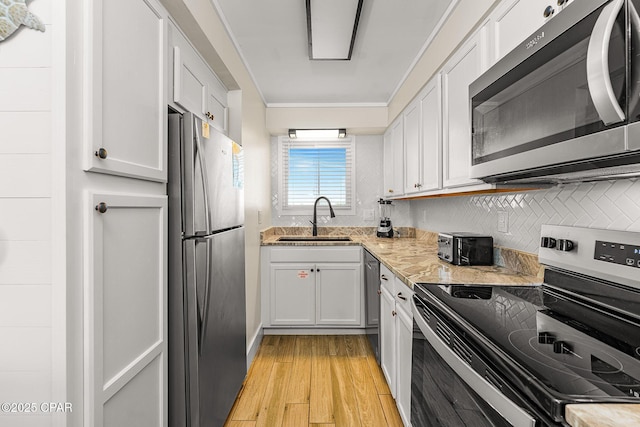 kitchen featuring appliances with stainless steel finishes, white cabinets, and a sink