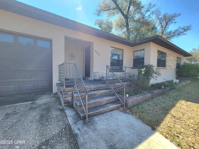 ranch-style home featuring driveway, an attached garage, and stucco siding