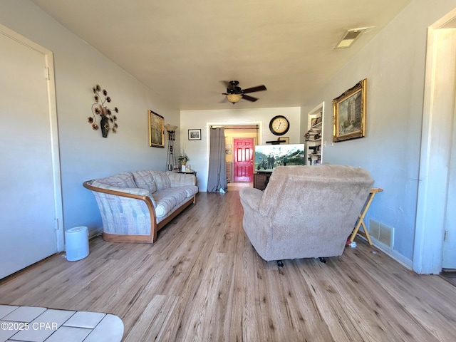 living area with wood finished floors, visible vents, and a ceiling fan