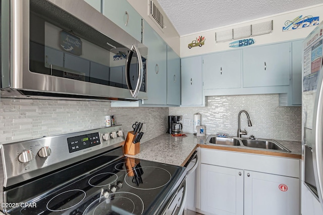 kitchen with stainless steel appliances, visible vents, decorative backsplash, a sink, and a textured ceiling