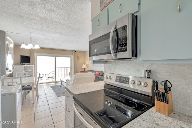 kitchen featuring light tile patterned floors, appliances with stainless steel finishes, a textured ceiling, and backsplash