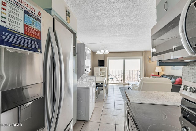 kitchen featuring light tile patterned floors, stainless steel appliances, light countertops, and stacked washer / drying machine