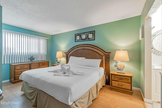 bedroom with light wood finished floors, baseboards, and a textured ceiling