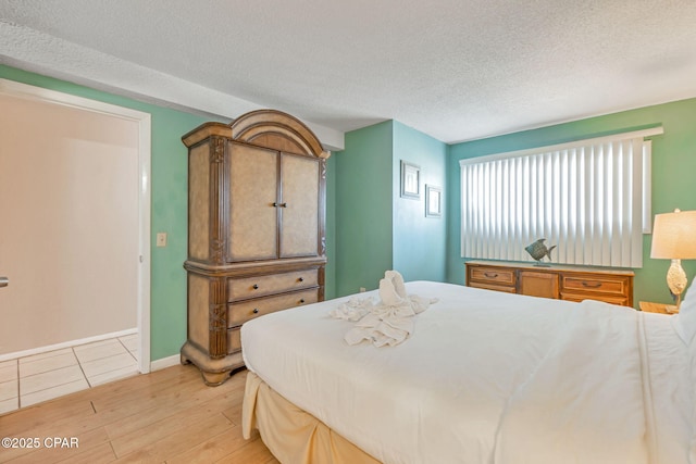 bedroom featuring light wood-style flooring, baseboards, and a textured ceiling