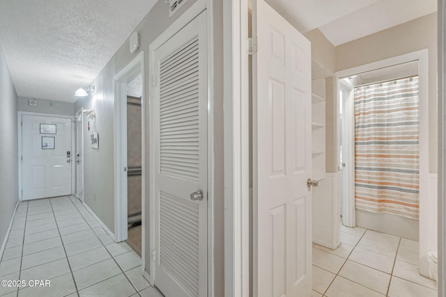 hallway featuring light tile patterned flooring and a textured ceiling