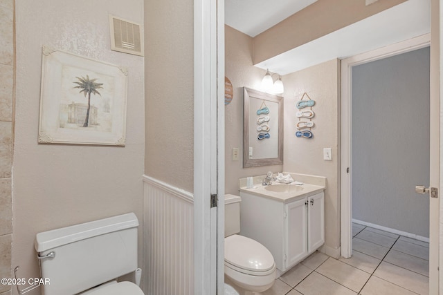 half bath featuring toilet, vanity, visible vents, and tile patterned floors