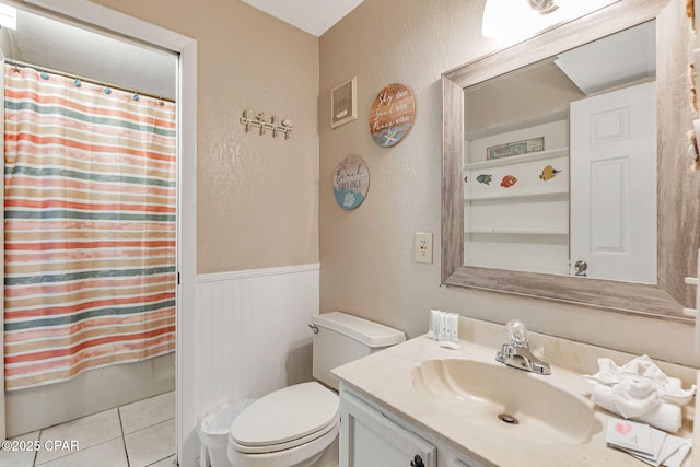 full bathroom with toilet, shower / tub combo, wainscoting, vanity, and tile patterned floors