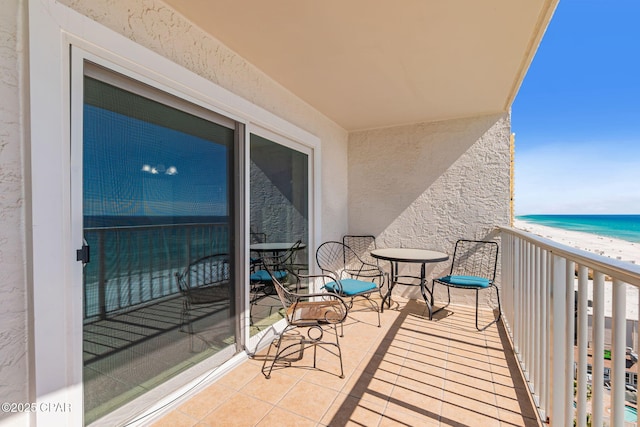 balcony with a water view and a view of the beach