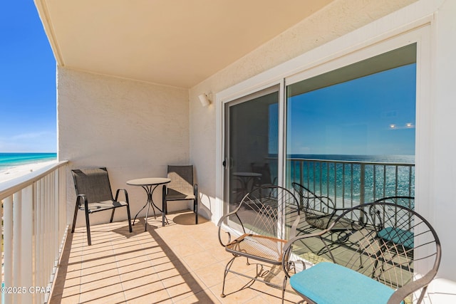 balcony with a water view and a view of the beach