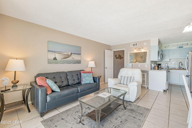 living area featuring visible vents, a textured ceiling, and light tile patterned flooring