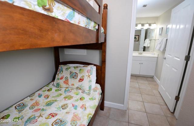 unfurnished bedroom with light tile patterned flooring, a sink, visible vents, baseboards, and ensuite bath