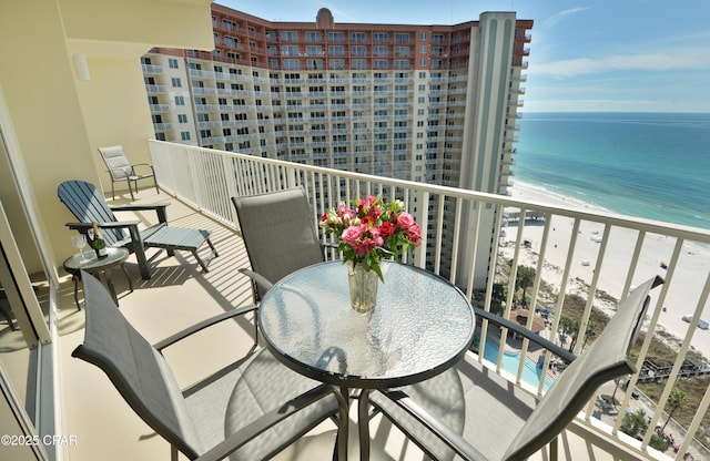 balcony featuring a water view, outdoor dining area, and a view of the beach